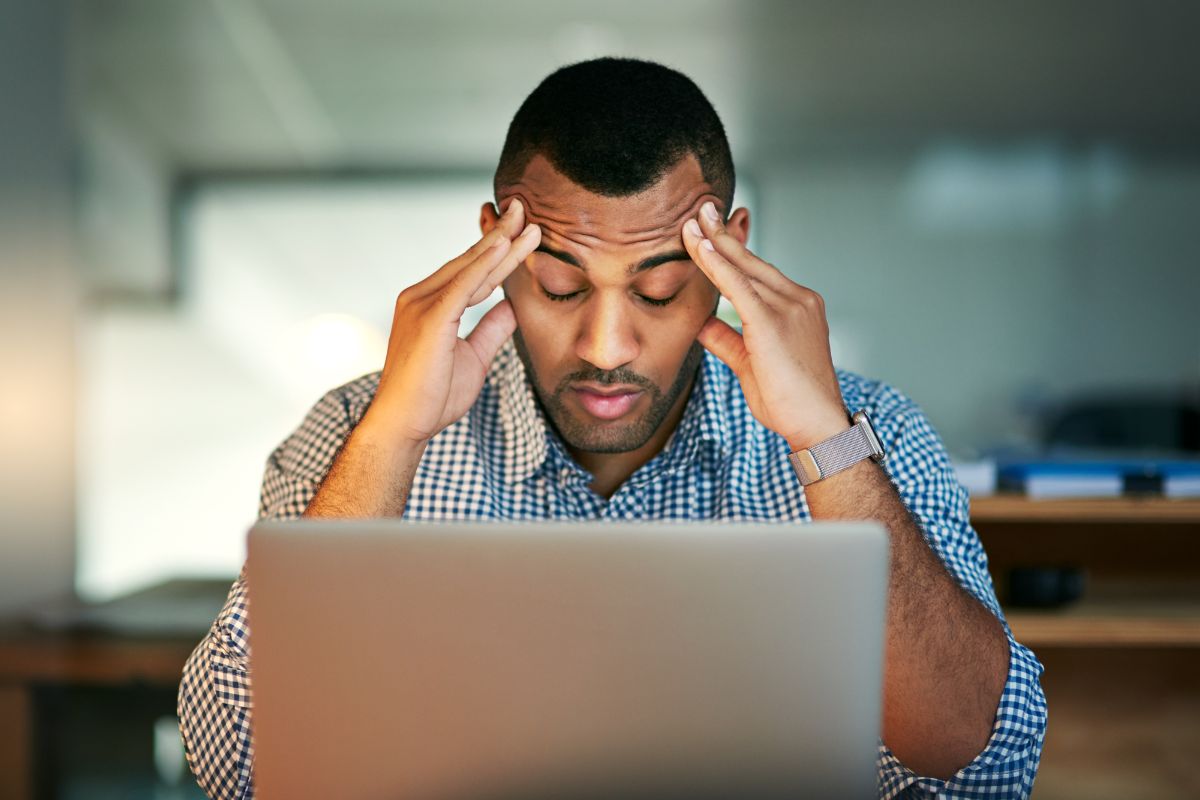 Tired man holding his head in front of a computer
