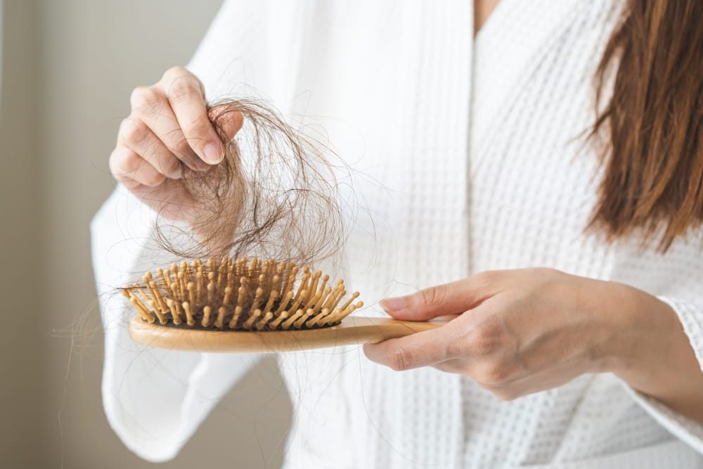 woman pulling hair from hair brush